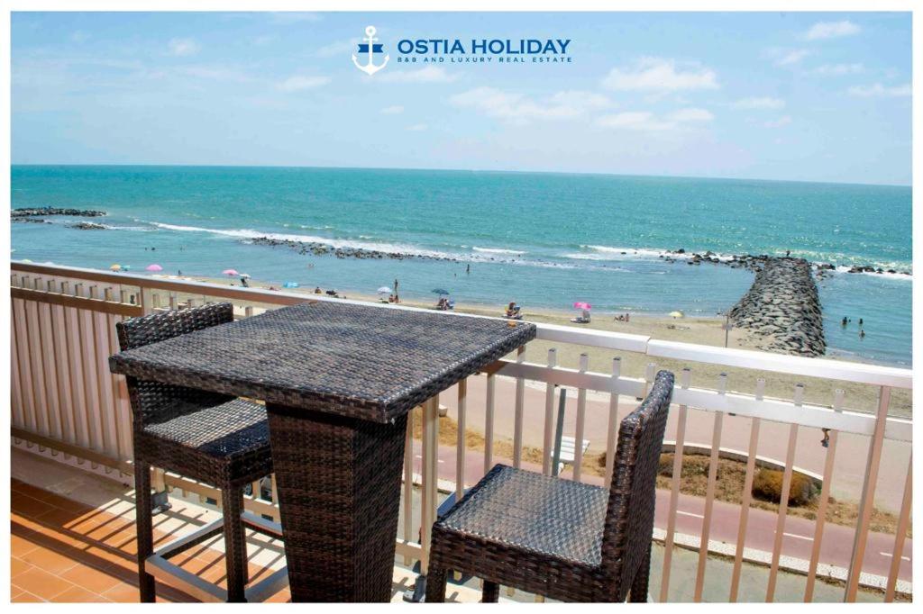 einen Tisch und Stühle auf einem Balkon mit Blick auf den Strand in der Unterkunft Ostia Holiday Sunset in Lido di Ostia