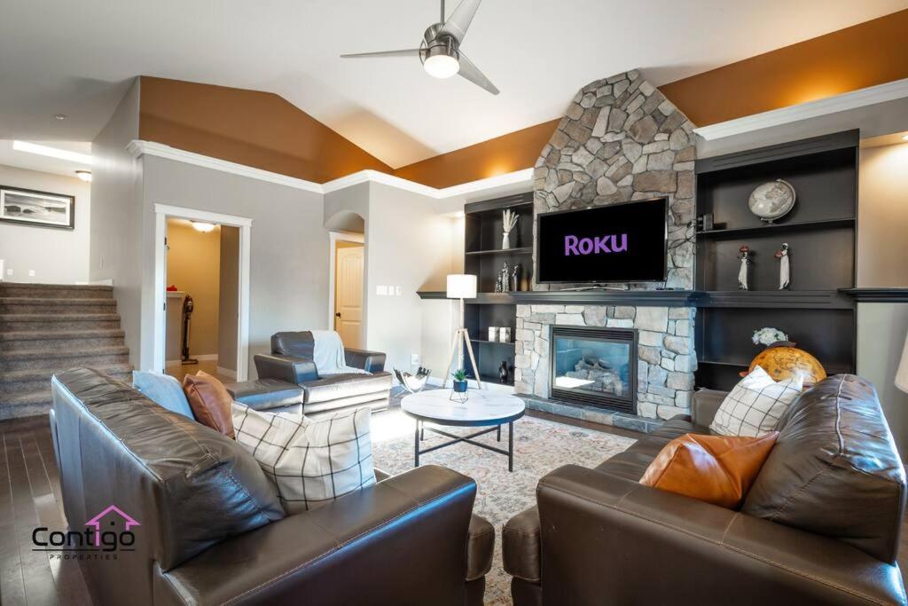 a living room with leather furniture and a fireplace at Luxury Retreat, Sleeps 12, AC, Patio, 5 min to YQL in Lethbridge