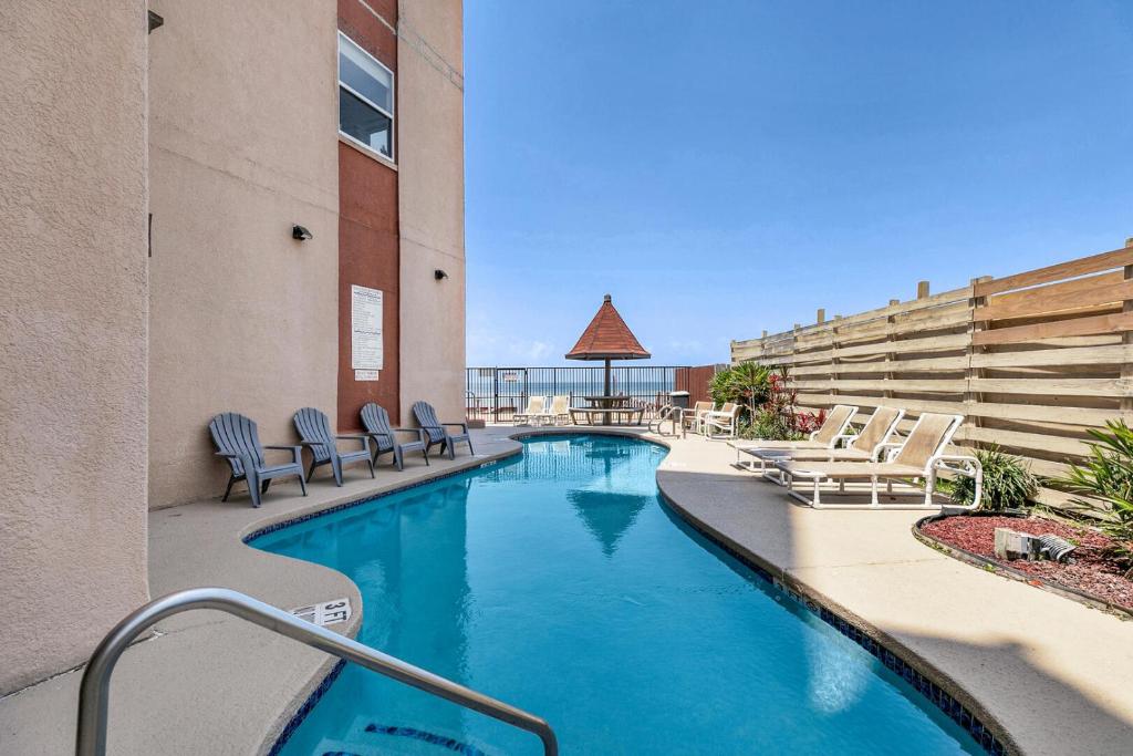 a swimming pool in a hotel with lounge chairs at Bayfront condo with water view & boat slips! in South Padre Island