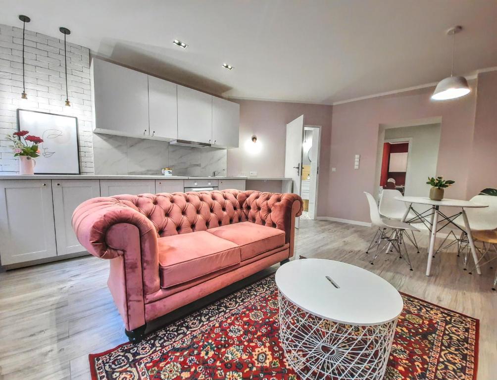 a living room with a pink couch and a table at Apartament Kwietniewskiego 4 Bytom in Bytom