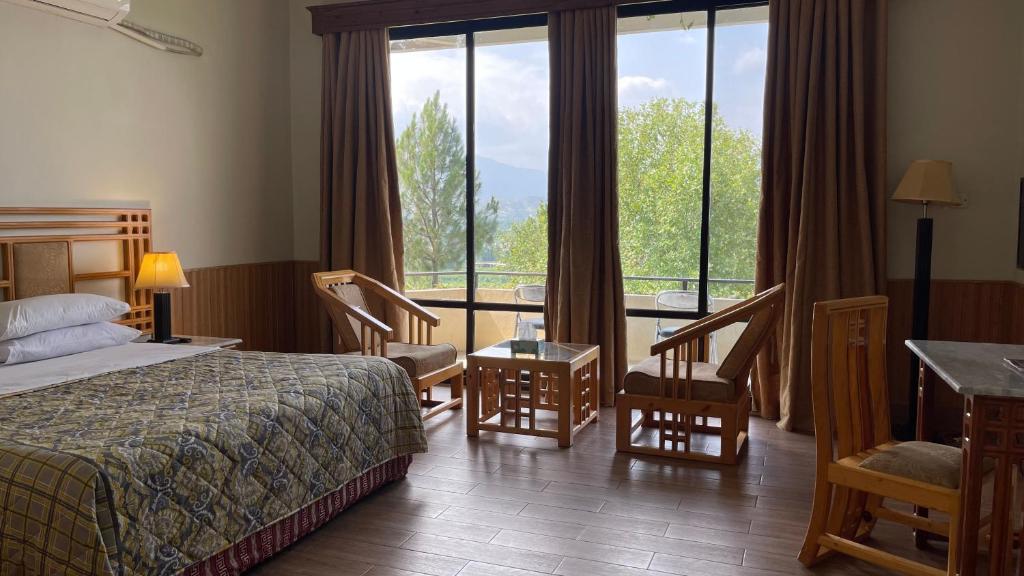 ein Hotelzimmer mit einem Bett und einem großen Fenster in der Unterkunft Rock City Resort in Mingora