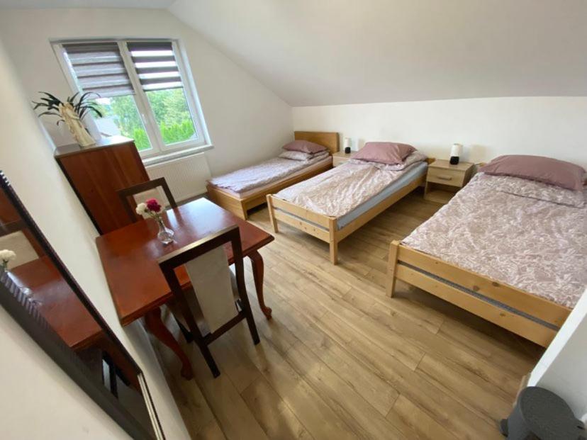 a room with two beds and a table and a desk at Noclegi Grojec 