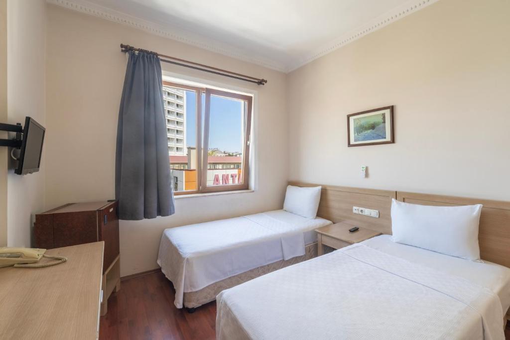 アンタルヤにあるŞehir Hotelのベッド2台と窓が備わるホテルルームです。
