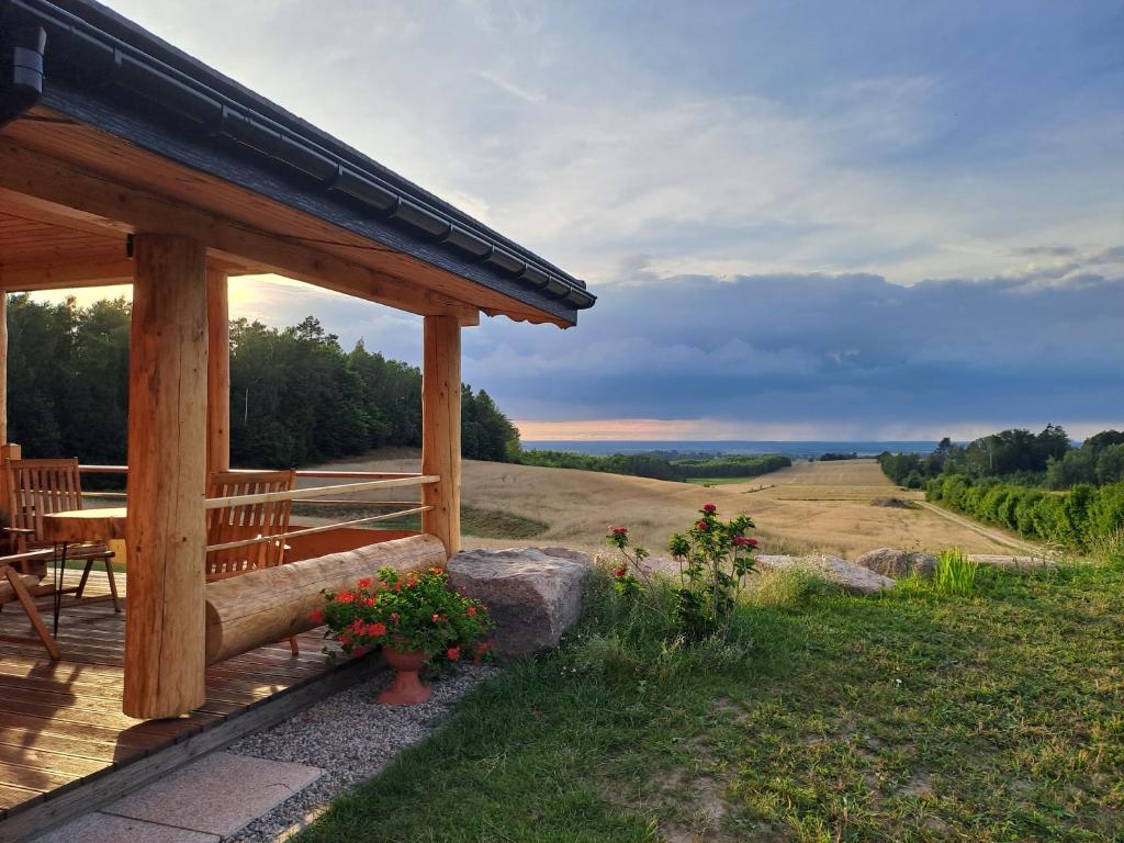 a wooden porch with a table and a view of a field at Dylewska Widokówka in Pietrzwałd