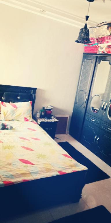 a bedroom with a bed and a black cabinet at شقة مجهزة للكراء في فرح السلام الألفة in Casablanca