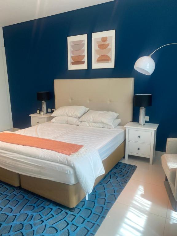 a bedroom with a large bed with a blue wall at Квартира студия Damac Maison Cour Jardin in Dubai