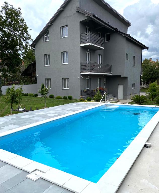 a house with a large blue swimming pool in front of a building at Apartmani Stefan in Vrdnik