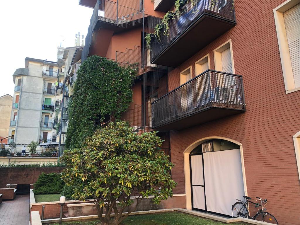 un edificio de ladrillo rojo con un árbol delante de él en Appartamento Gio, en Novara