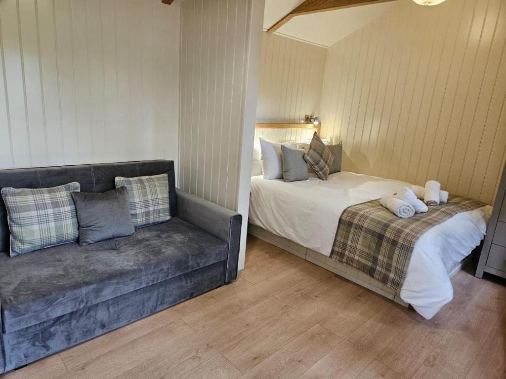 a living room with a couch and a bed at Woodland Shepherds Hut - 'Saga' in Caernarfon