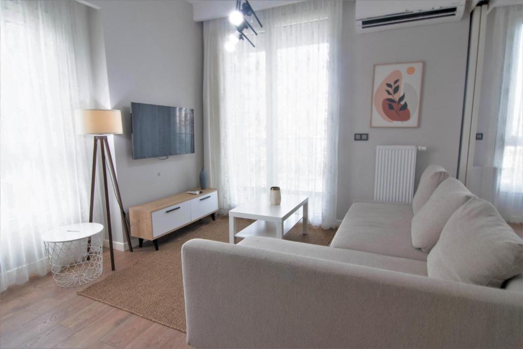 a living room with a white couch and a tv at Modern City Getaway - Immerse Yourself In Luxury in Istanbul