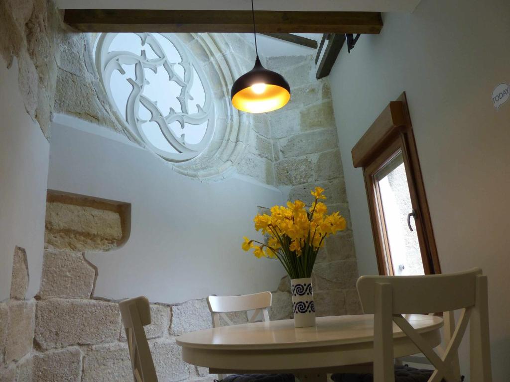 une table et des chaises avec un vase de fleurs jaunes dans l'établissement Apartamento Ábside de San Juan III, à Estella