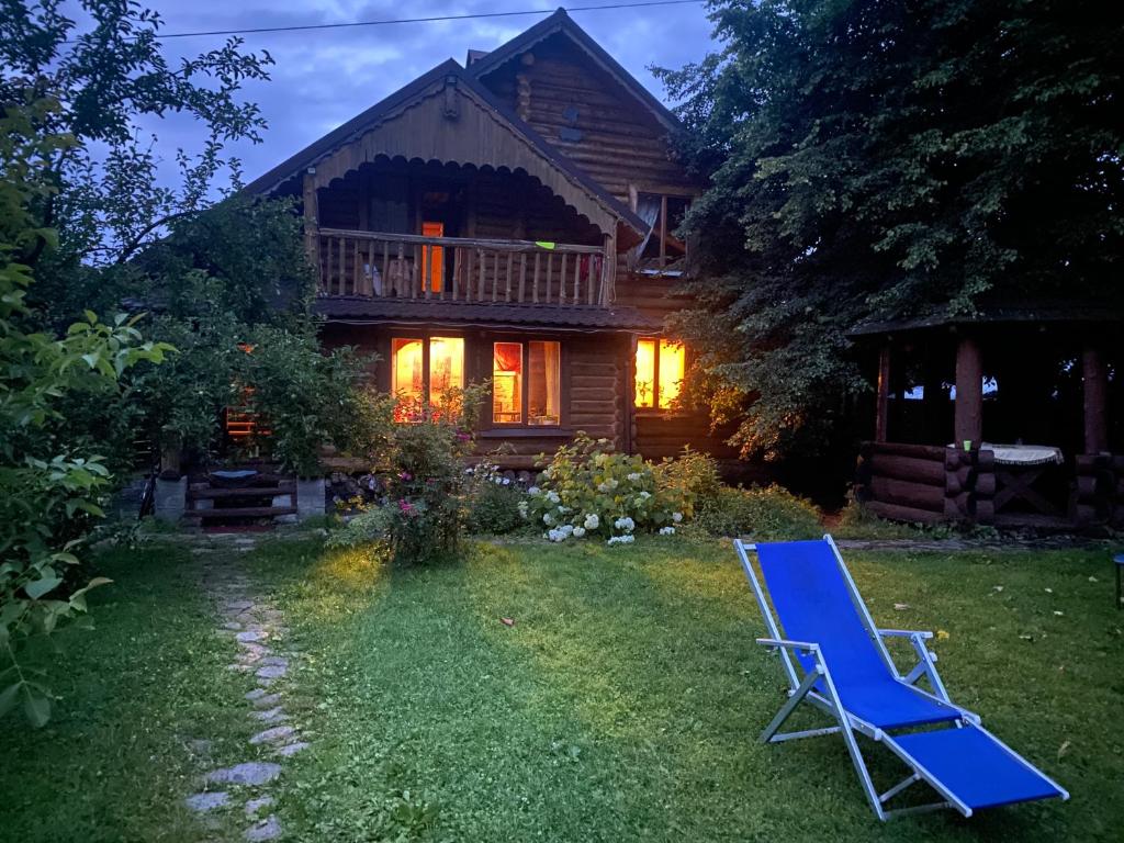 a blue lawn chair in front of a house at Oselia Mandrivnykiv in Tukhlya