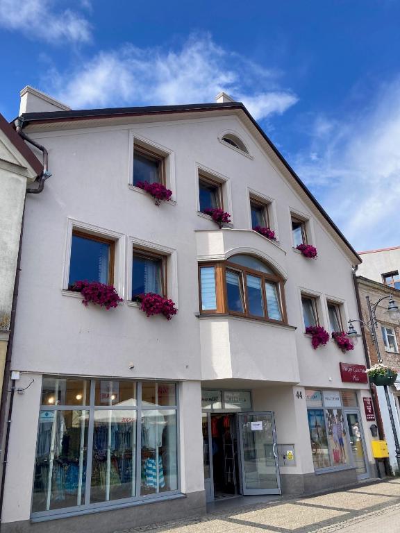 a white building with flowers in the windows at Pokoje Gościnne PLUS in Ustka
