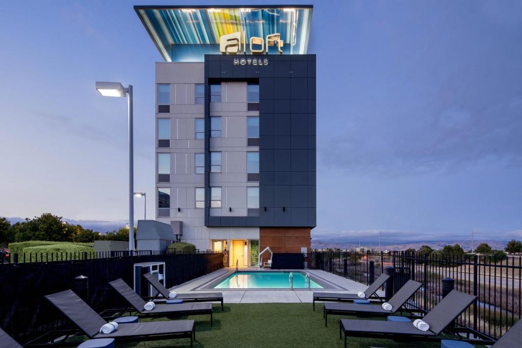 a hotel with a swimming pool and lounge chairs at Aloft Santa Clara - San Jose North in San Jose