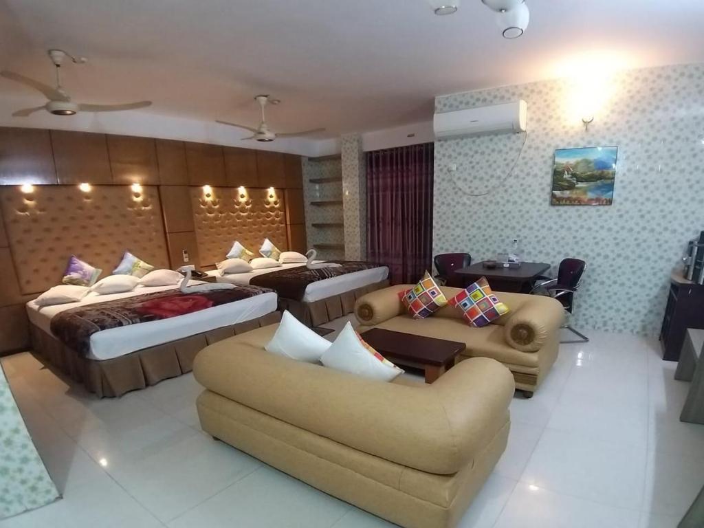 une chambre d'hôtel avec deux lits et un canapé dans l'établissement Saint Martin Resort, à Cox's Bazar