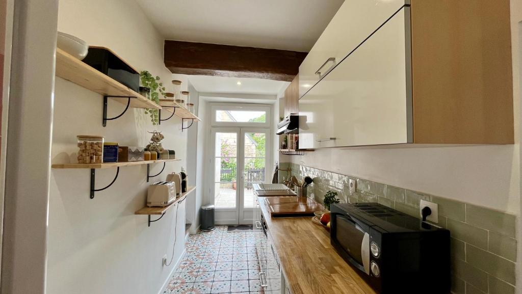 a kitchen with a sink and a microwave in a room at L&#39;Escapade de Pierrefonds par Your Sweet Loc in Pierrefonds