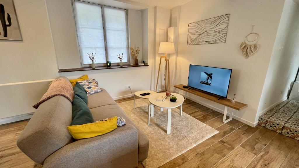 a living room with a couch and a tv at L&#39;Escapade de Pierrefonds par Your Sweet Loc in Pierrefonds