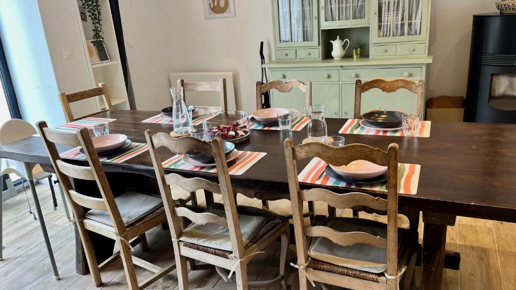 a dining room table with chairs and a wooden table with plates at L&#39;Escapade de Pierrefonds par Your Sweet Loc in Pierrefonds