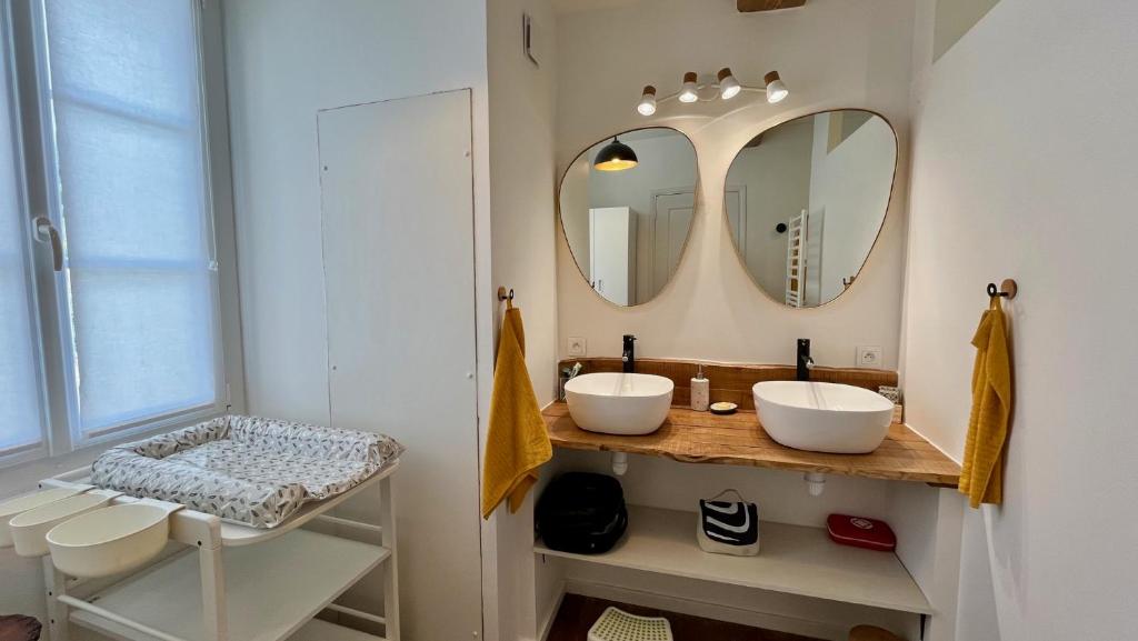 a bathroom with two sinks and two mirrors at L&#39;Escapade de Pierrefonds par Your Sweet Loc in Pierrefonds