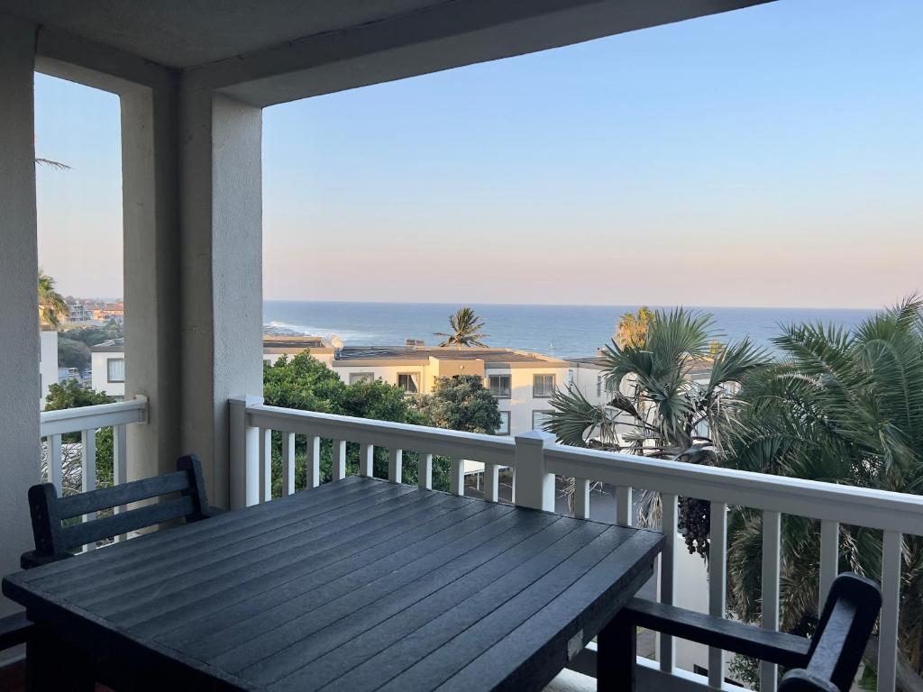 uma mesa de madeira numa varanda com vista para o oceano em 196 Laguna La Crete em Uvongo Beach