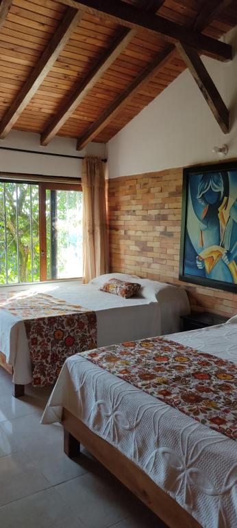 a bedroom with two beds and a painting on the wall at Hotel Chalet San Juan de Ticlan in Armenia