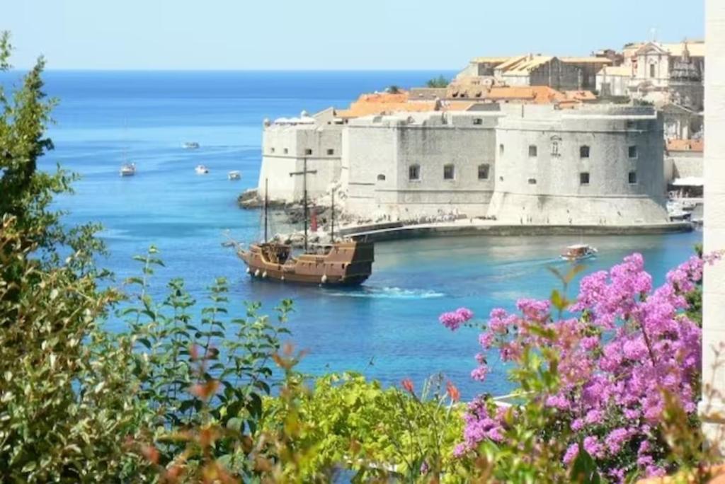 a boat in the water next to a building at Apartments Emi in Dubrovnik