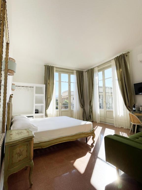 1 dormitorio con 1 cama blanca grande y ventanas en B&B ISOLA Messina, en Messina
