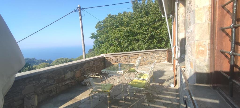 eine Terrasse mit einem Tisch und Stühlen an der Wand in der Unterkunft Forest, Sea, Stone Villa in Mouresi