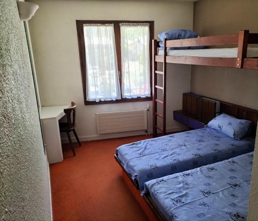 a bedroom with two bunk beds and a desk at Chambre Triple avec Salle de Bains Privative 3 in Vallouise