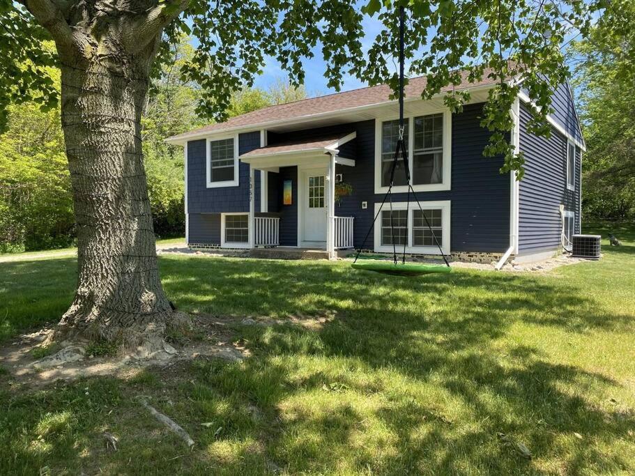 a blue house with a tree in the yard at BlueHaven: Your Cozy Lakeside Retreat in Glenn