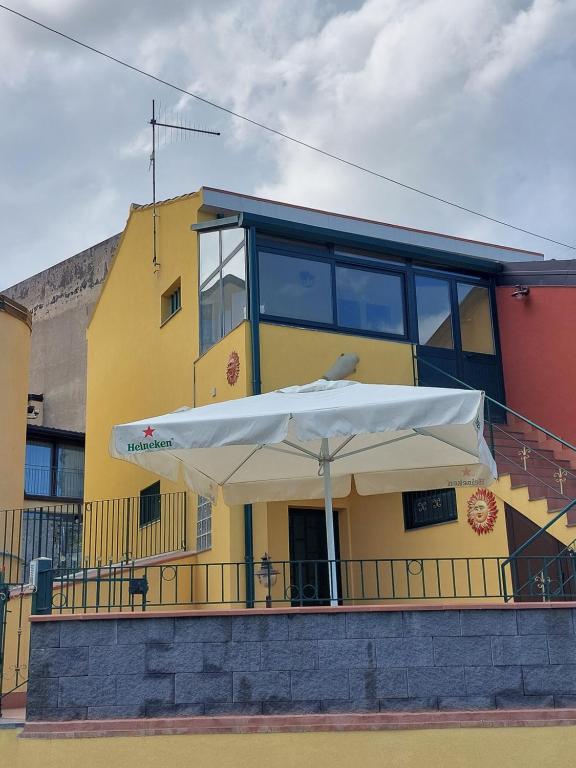 a yellow building with a white umbrella in front of it at CASA VACANZA DEL SOLE in Milo