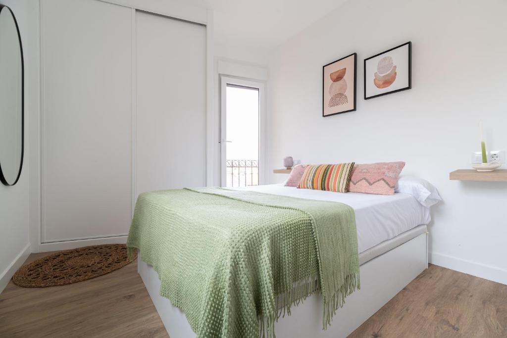 - une chambre blanche dotée d'un lit avec une couverture verte dans l'établissement La Terracita, à Vigo