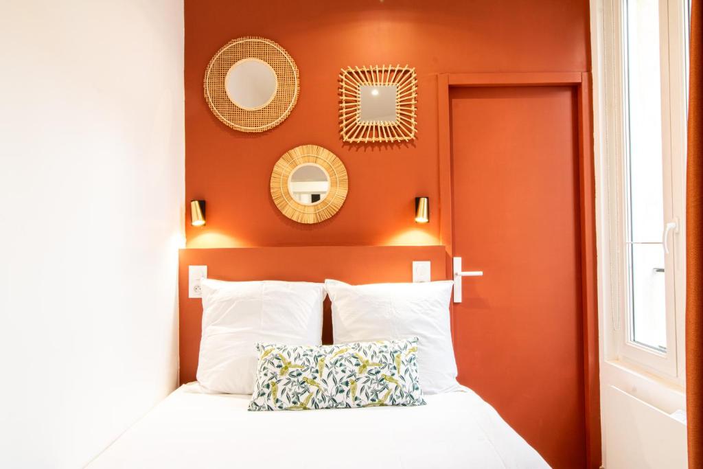 une chambre avec un lit aux murs orange et aux miroirs dans l'établissement Appartement Cosy Nîmes-Centre 2, à Nîmes