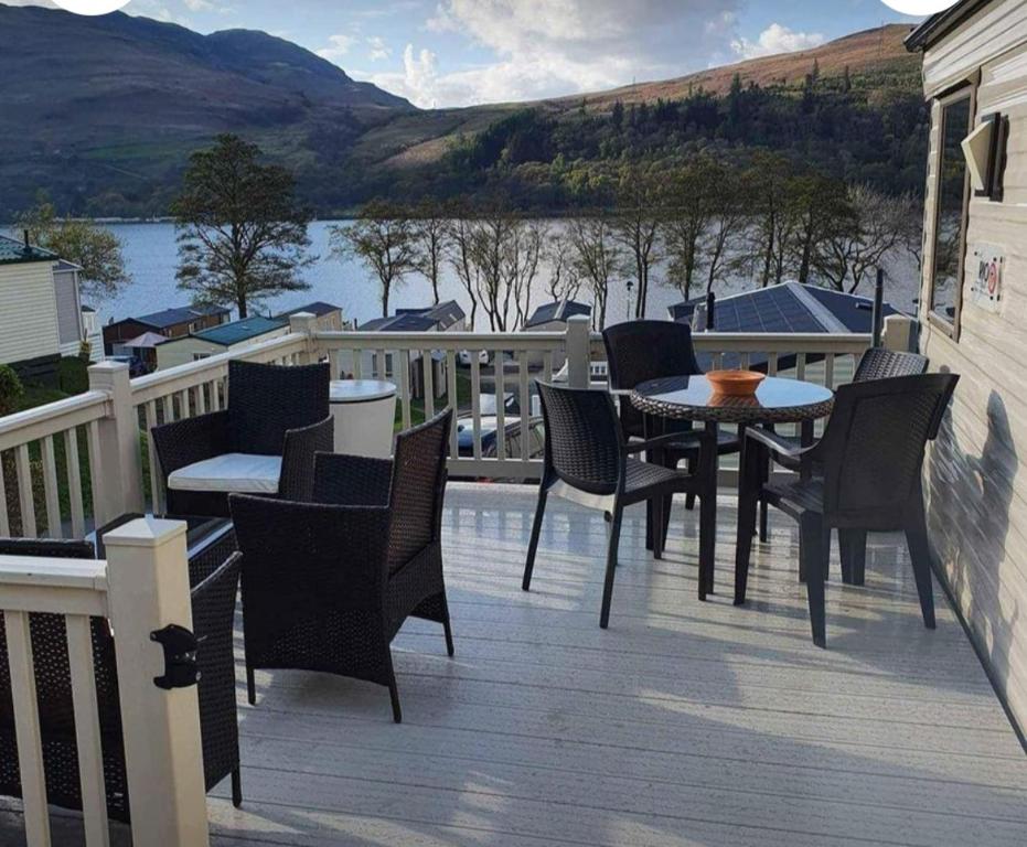 a deck with a table and chairs and a view of a lake at Loch Earn Holiday Home in Saint Fillans