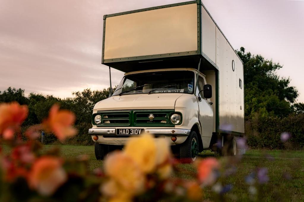 an old white truck parked in a field with flowers at Vintage '79 Bedford Wild Camping Truck near St Ives in Tuckingmill