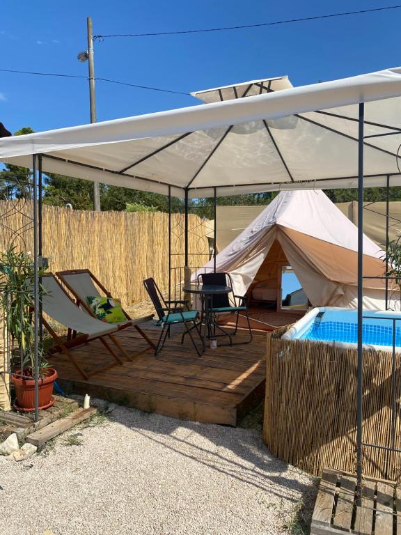 Tienda con mesa, sillas y piscina en Camping Perla en Zadar