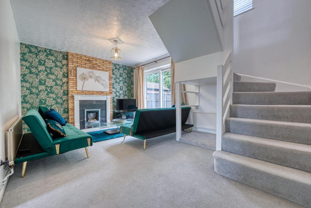 a living room with a staircase and a green couch at CAPRI 13 SA - 3 bed House, Close to Loughborough University & M1 motorway, Free Wifi, Big garden, Ample parking- Ask for contractor rates! in Loughborough