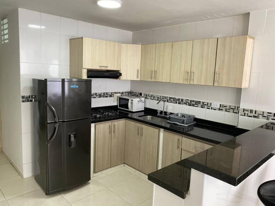 a kitchen with a black refrigerator and wooden cabinets at La Morada del Sur in Floridablanca