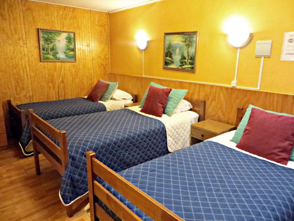 a hotel room with two beds and two lamps at Hostal Remember in Temuco