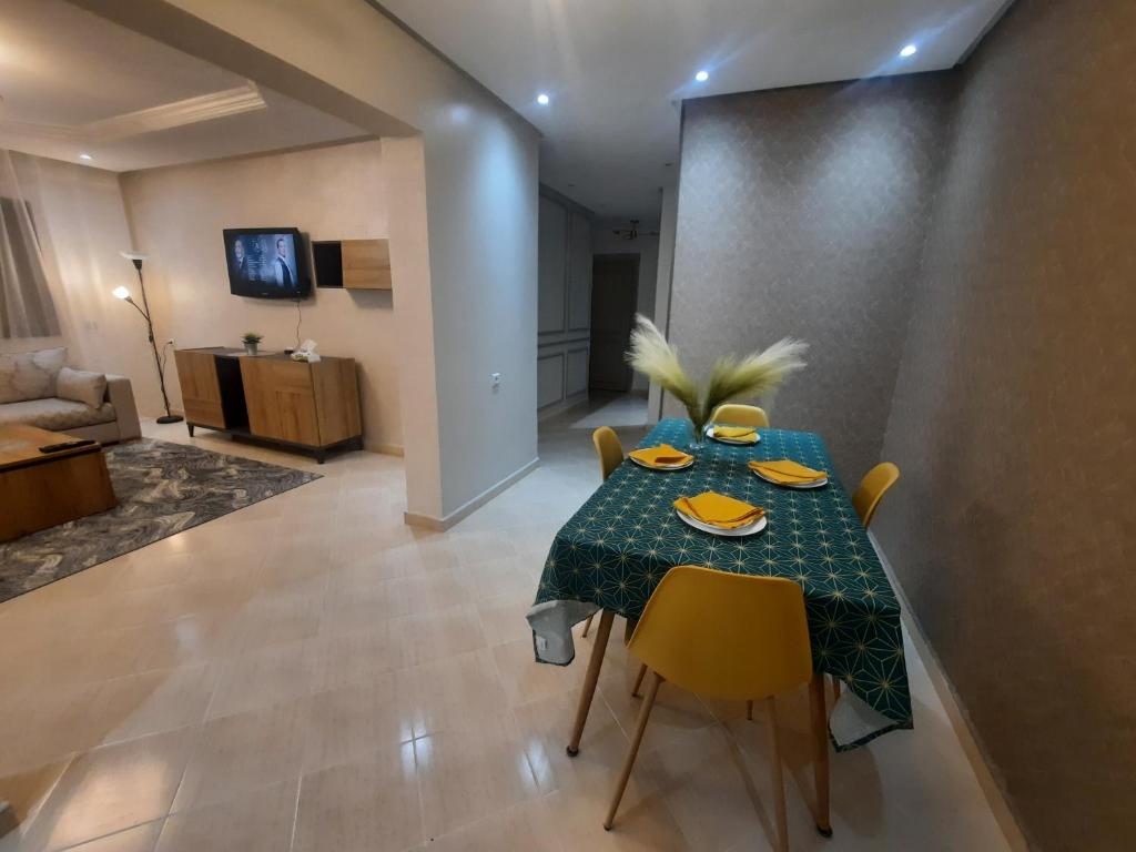 uma mesa de jantar com uma toalha de mesa verde e cadeiras amarelas em magnifique appartement em Tânger