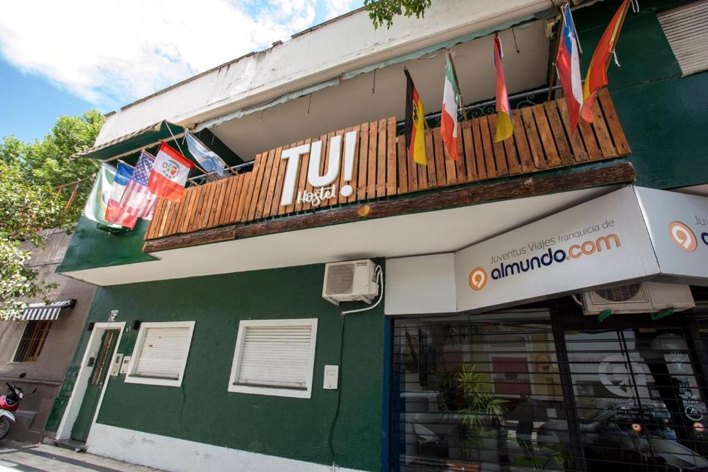 a green building with flags hanging from a balcony at Tu Hostel Tucuman in San Miguel de Tucumán