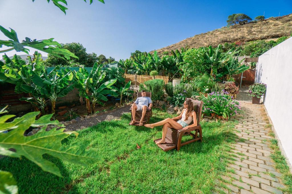een man en een vrouw zittend in stoelen in een tuin bij CASA EMBLEMÁTICA MARUCA y LELI in Los Silos