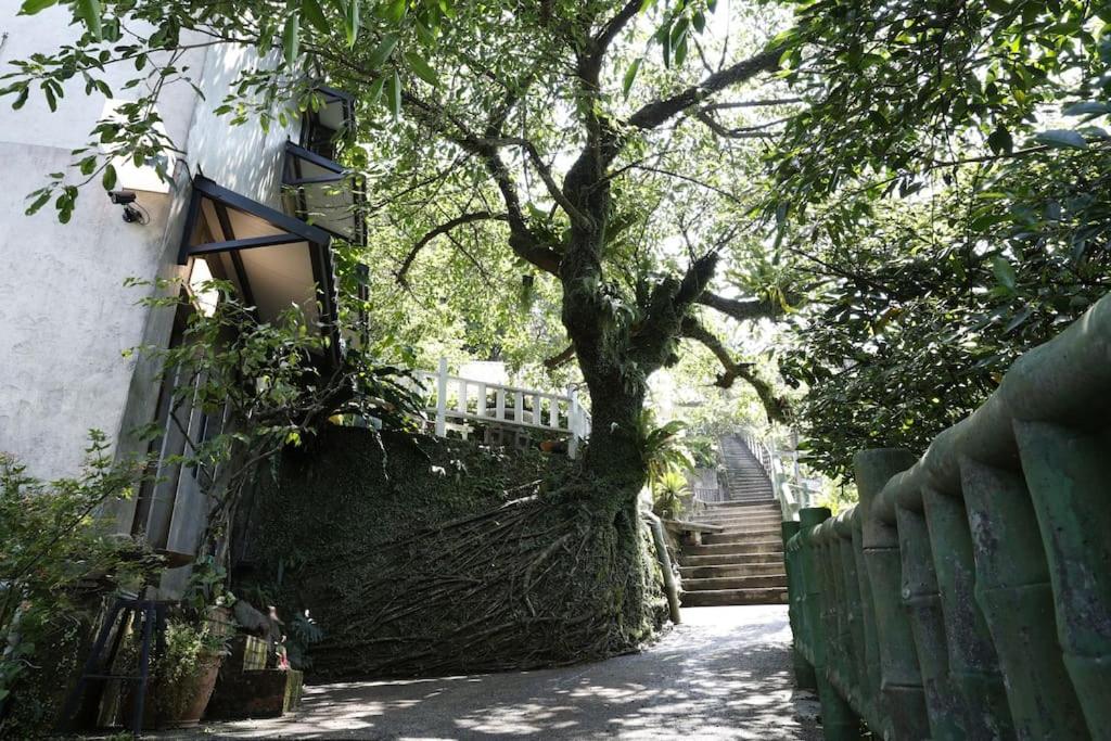 瑞芳區的住宿－濦崌四季 l'ermite，树从房子旁边的围栏里长出来
