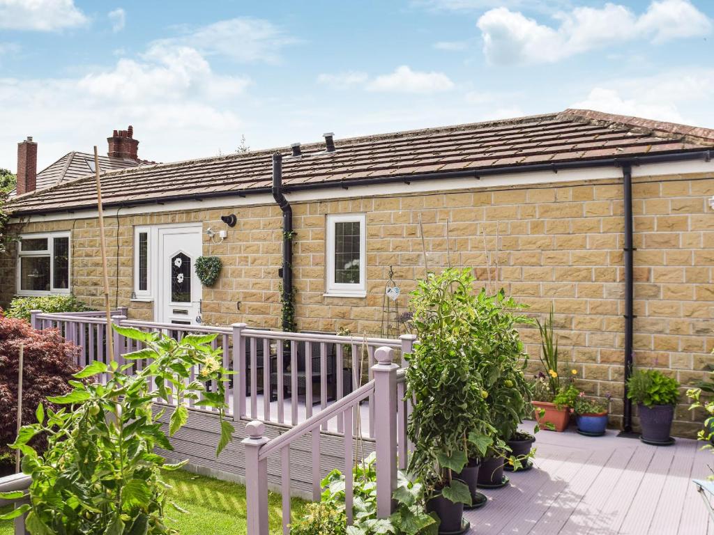 a brick house with a wooden deck in front of it at Lilly Lodge in Almondbury