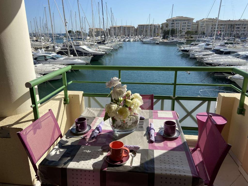 - une table avec un vase de fleurs sur un balcon avec des bateaux dans l'établissement Confortable appt 2 pièces avec grande terrasse, clim, garage, proche mer et commerces - FR-1-226A-165, à Fréjus