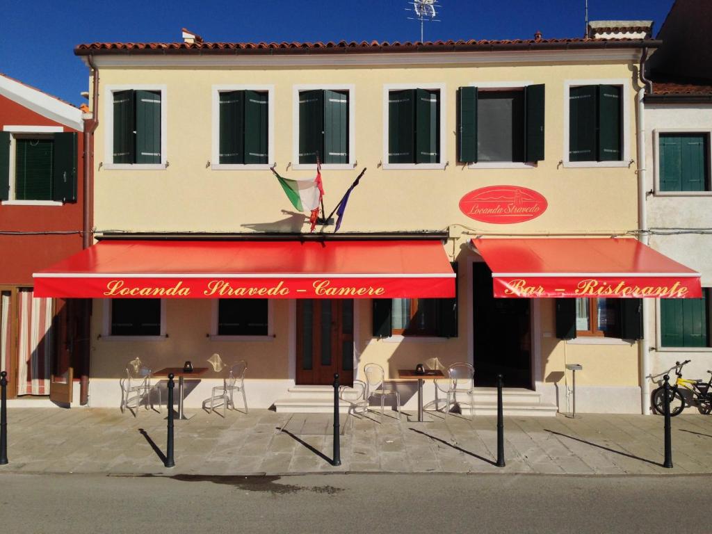 un ristorante con ombrelloni rossi di fronte a un edificio di Locanda Stravedo a Pellestrina