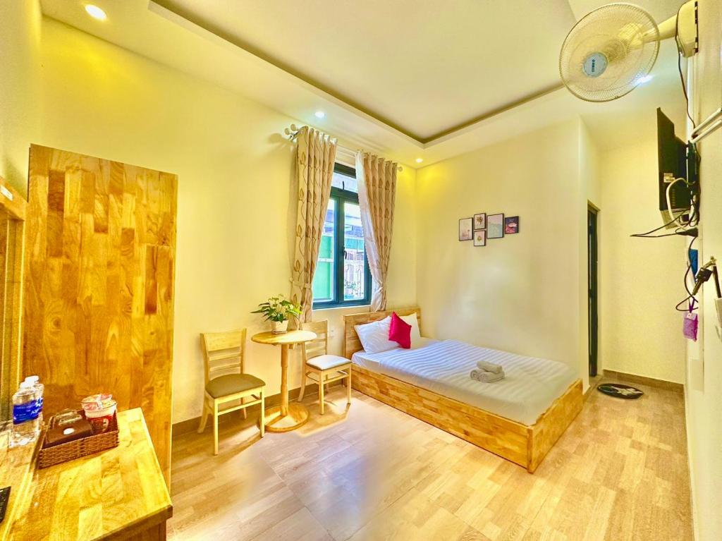 1 dormitorio con 1 cama, mesa y sillas en Khách Sạn Minh Hà Đà Lạt en Da Lat