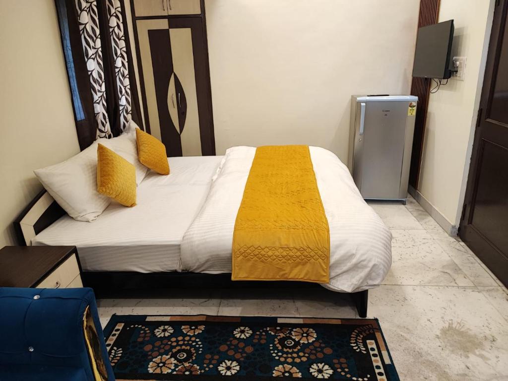 ein Schlafzimmer mit einem Bett mit einer gelben und weißen Decke in der Unterkunft Sun Moon Residency and Apartments, Hotels in Rohini in Neu-Delhi