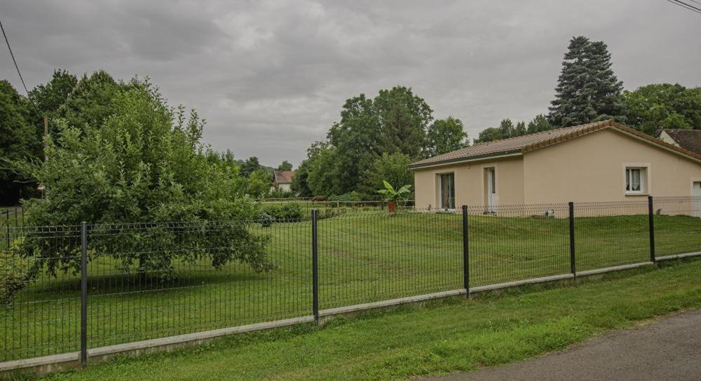 a fence in front of a yard with a house at La petite maison rose in Saint-Mards-en-Othe