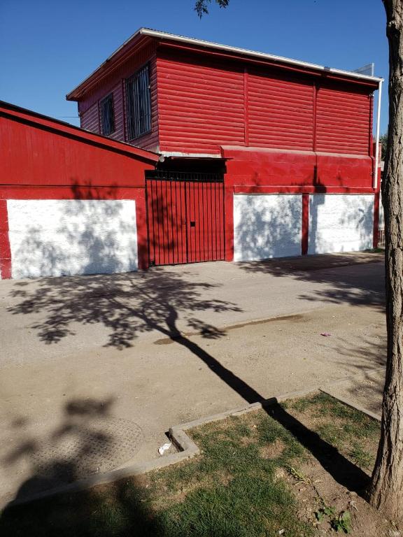 un edificio rojo y blanco con un árbol delante de él en Hospedaje Pudahuel en Santiago